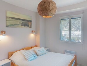 Quarto com cama, duas luminárias de cabeceira, um quadro na parede e uma janela com vista.