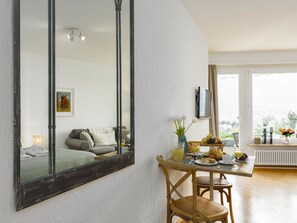 A dining area with a table set for breakfast, a large mirror on the wall, and a view of the outdoors through the window.
