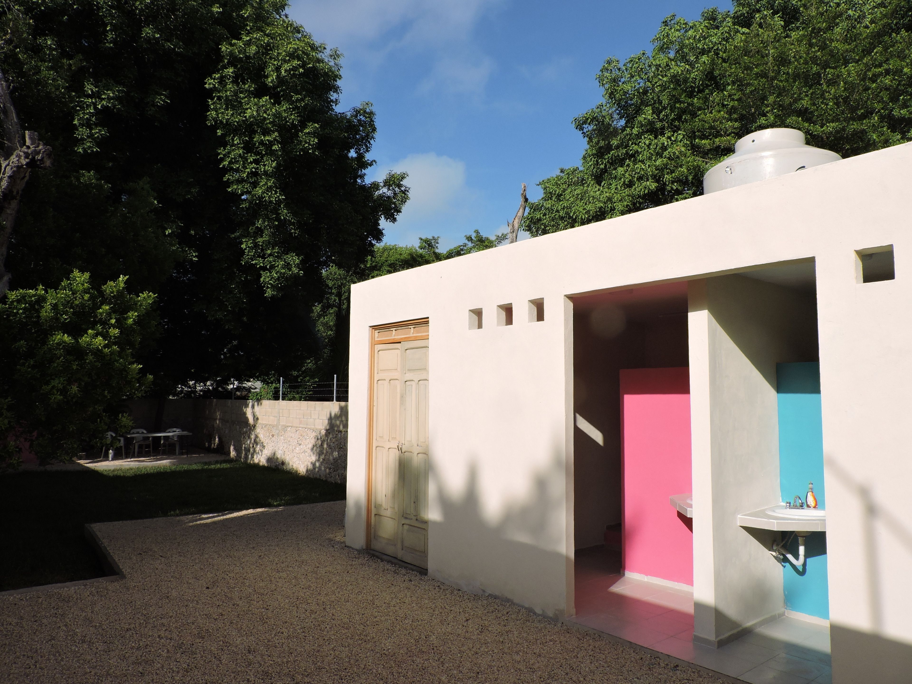 A modern, minimalist building with a white exterior, a wooden door, and a pink interior.