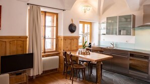 A cozy kitchen with wooden cabinetry, a dining table, and a built-in oven. - Chesa Chascharia 1 by Interhome (Samedan)