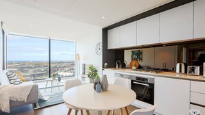 A modern kitchen with a large island, white cabinetry, and a view of the city.