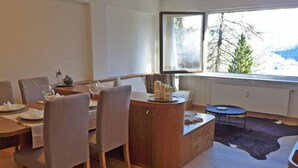 Un espace repas moderne avec une table en bois, des chaises à revêtement gris et une petite table ronde avec un plateau bleu.