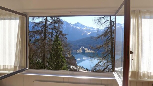 Une pièce dotée d’une grande fenêtre donnant sur un lac et des montagnes.