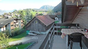 A balcony with a view of a village, a wooden building, and a table with chairs. - Apartment Ladasa by Interhome (Emmetten)