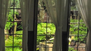 A room with large windows, curtains, and a view of a lush garden. - Camelia Inn Yukitsubaki (Kanazawa)