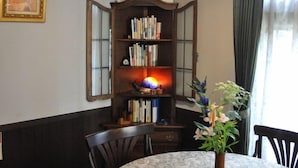 A dining area with a round table, chairs, a bookshelf, and a hanging light fixture. - Camelia Inn Yukitsubaki (Kanazawa)