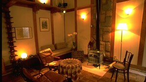 A cozy room with a fireplace, a sofa, a round table, and a chair. - Camelia Inn Yukitsubaki (Kanazawa)