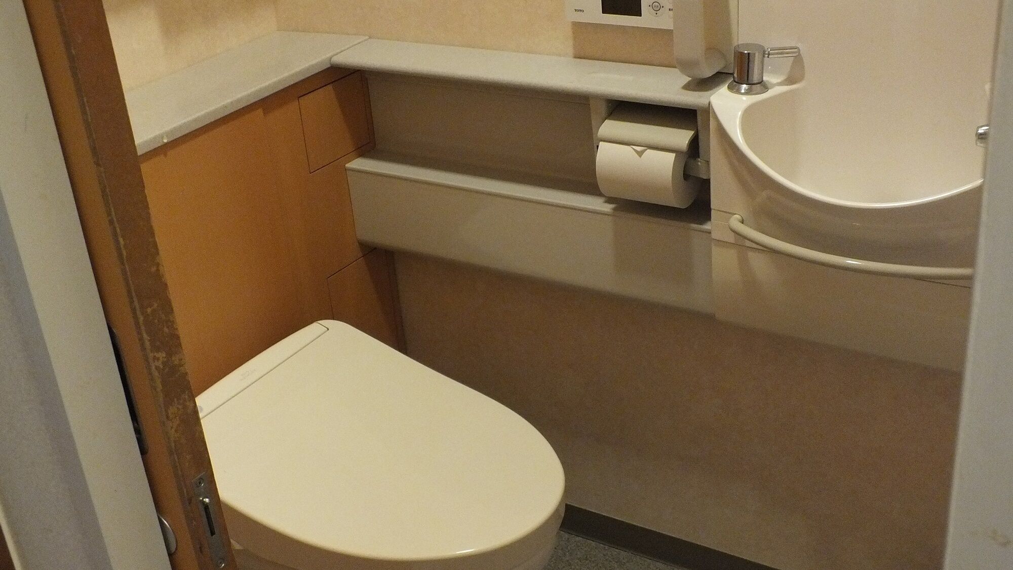 Un baño pequeño con inodoro, lavabo y dispensador de papel higiénico.