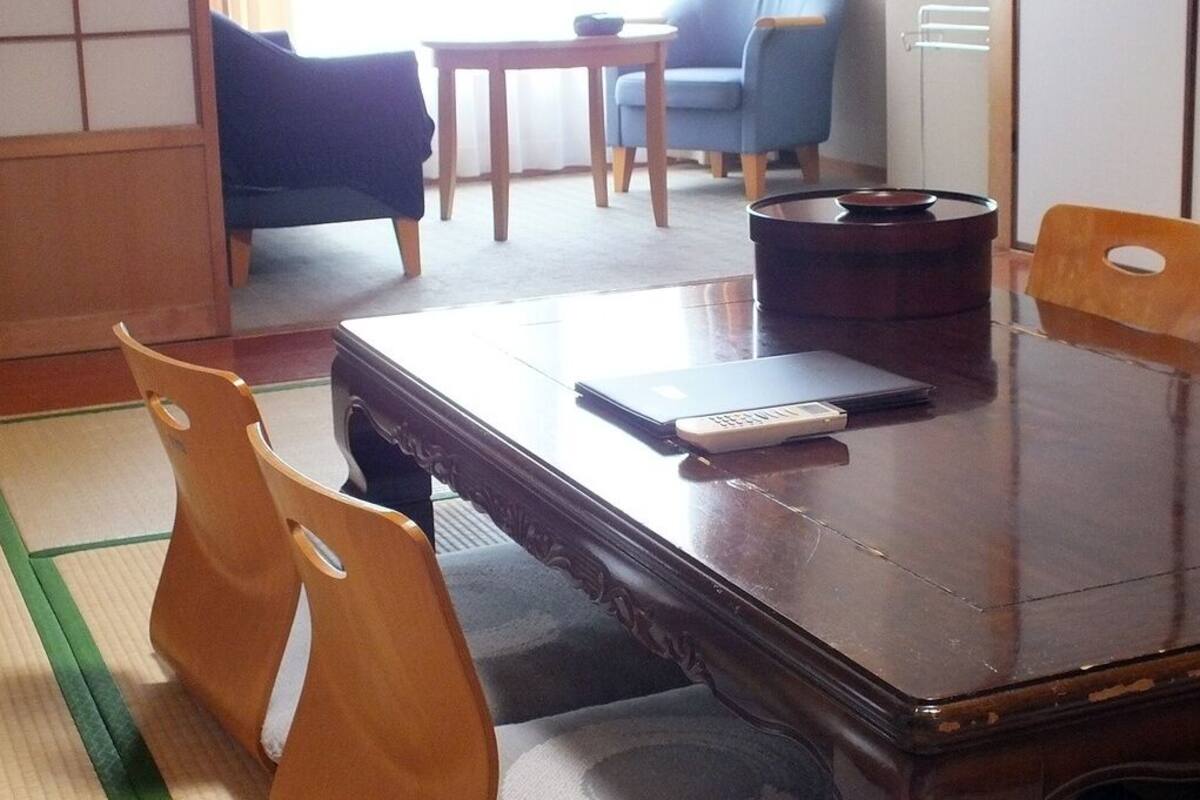 Una habitación tradicional japonesa con suelo de tatami, una mesa de madera oscura y sillas de madera.