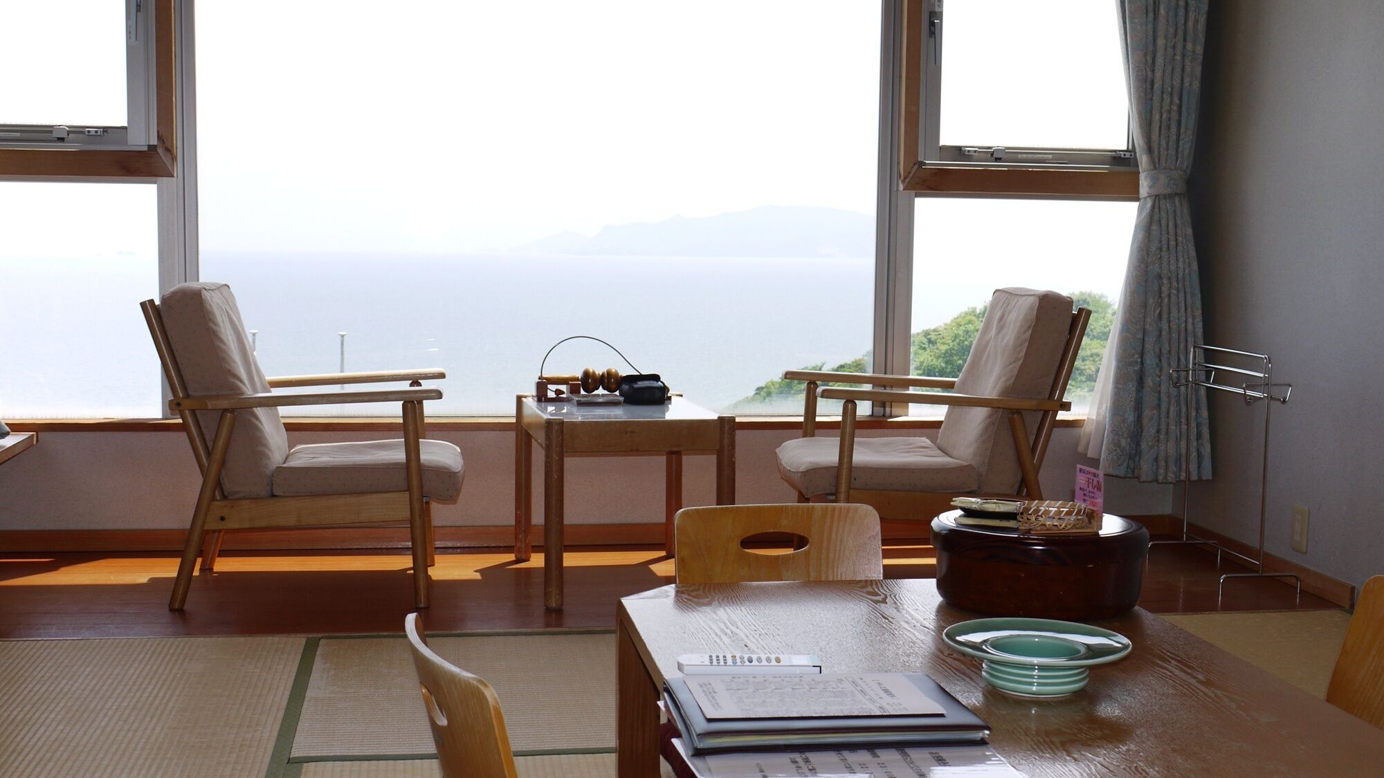 A room with two chairs, a table, and a view of the sea.