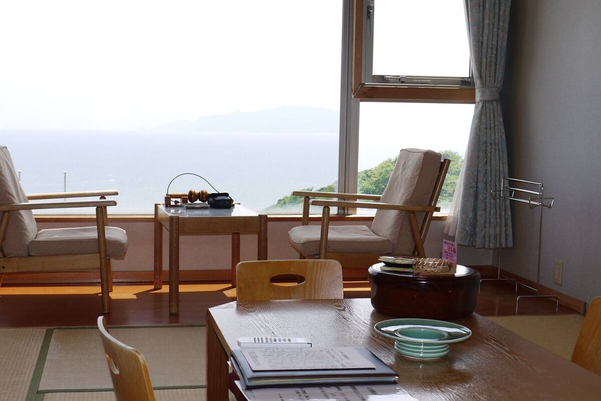 Una habitación con dos sillas, una mesa y vistas al mar.