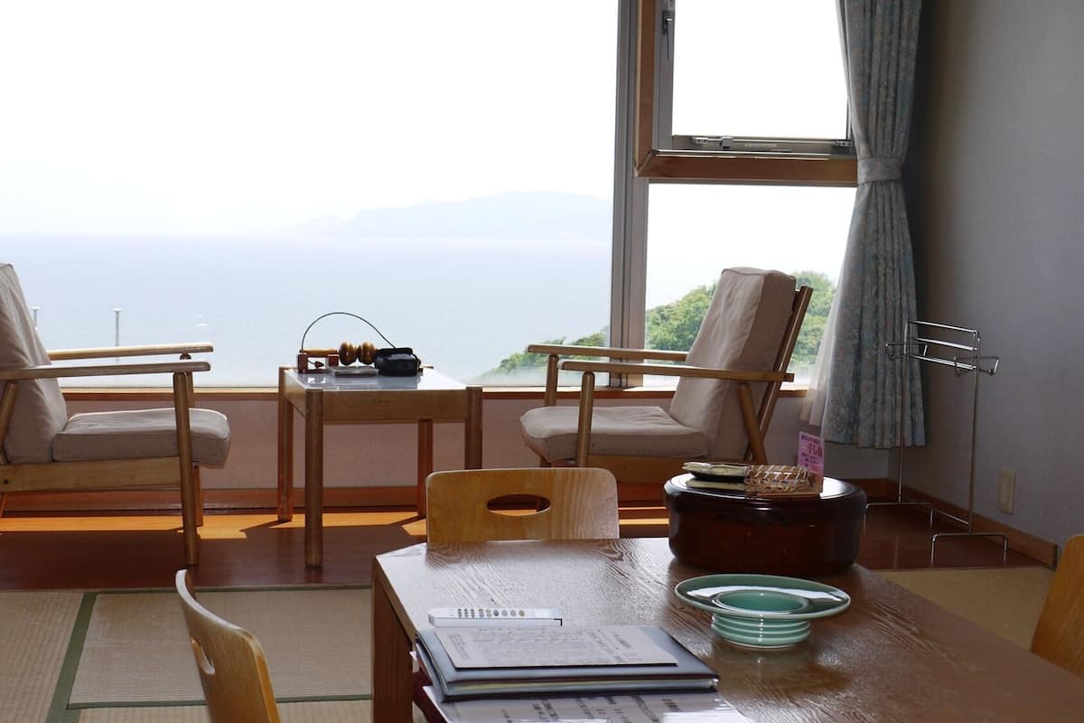 Una habitación con dos sillas, una mesa y vistas al mar.