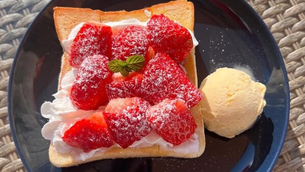 Un plato de postre con fresas, crema batida y una porción de helado.