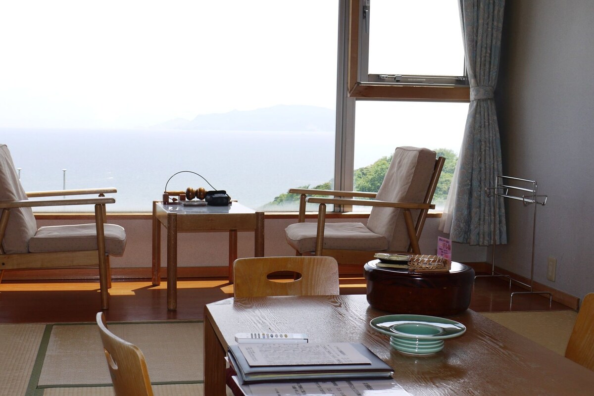 Ein Zimmer mit zwei Stühlen, einem Tisch und Meerblick.