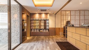 A hotel reception area with a wooden reception desk, a shoe display, and a modern interior design. - Super Hotel Anan Tomioka (Anan)
