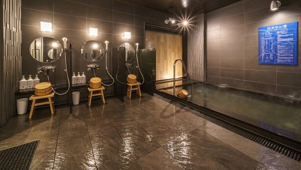 A modern bathroom with multiple shower stalls, a large mirror, and a sauna area. - Super Hotel Anan Tomioka (Anan)
