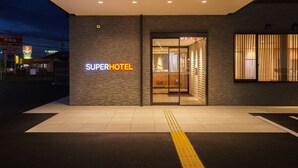 A hotel entrance with a modern design, featuring a prominent 'Super Hotel' sign and a glass door entrance. - Super Hotel Anan Tomioka (Anan)