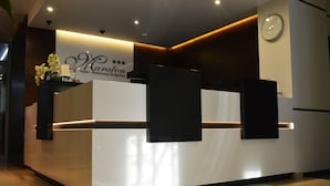 A hotel reception desk with a modern design, a clock on the wall, and a sign indicating the hotel name. - Hotel Maraton (Bydgoszcz)