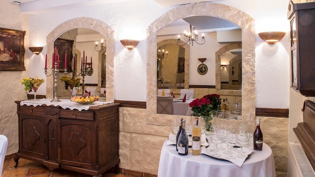 A dining area with a wooden cabinet, a table set for a meal, and a mirror reflecting the room. - Hotel Maraton (Bydgoszcz)