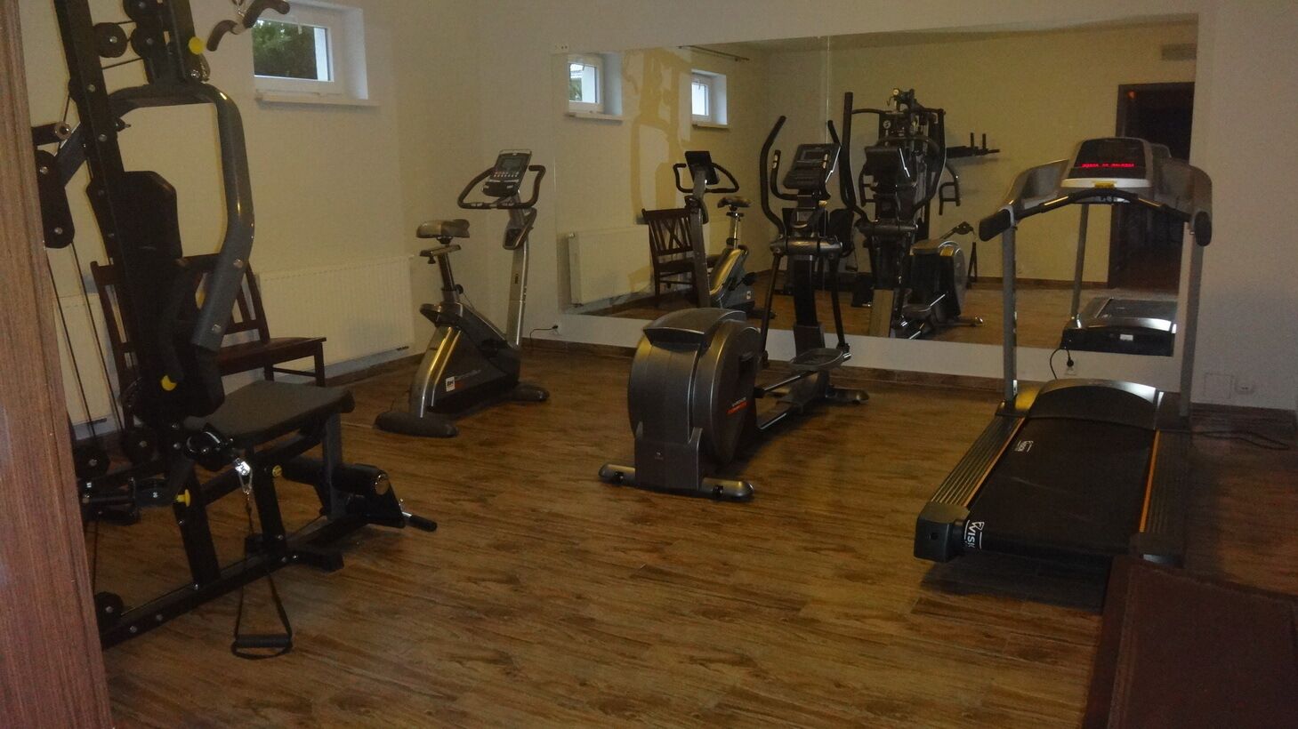 A home gym with various exercise equipment including a treadmill, stationary bike, and weight machines.