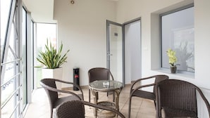 A balcony with wicker chairs, a glass table, and potted plants. - Hotel Maraton (Bydgoszcz)