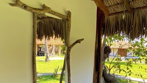 A rustic interior with a thatched roof, a wooden door frame, and a view of a well-maintained garden. - Le Marin Hotel Boutique (Barreirinhas)