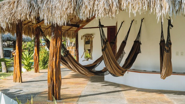 A hammock setup under a thatched roof, with a stone pathway and tropical plants. - Le Marin Hotel Boutique (Barreirinhas)