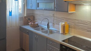 A compact kitchen with grey cabinets, a stainless steel sink, a microwave, and a stove. - Apartment in Nin with Terrace, Air condition, WIFI (3718-1) (Nin)