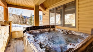 Un jacuzzi en una cabaña de madera con vistas a montañas nevadas.
