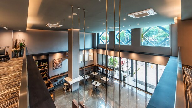 Een modern interieur met een eethoek, hoge plafonds en grote ramen met uitzicht op het buitengebied.