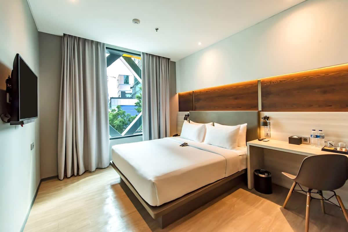 Une chambre d’hôtel moderne équipée d’un lit, d’un bureau, d’une chaise et d’un téléviseur.