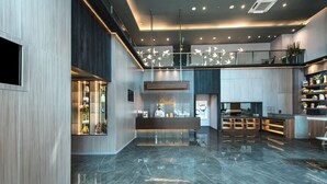 Een moderne hotellobby met een receptiebalie, een zithoek en een keuken in de achtergrond.