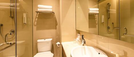 Un baño moderno con ducha de vidrio, inodoro y lavamanos con espejo.