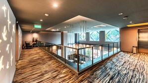 Een moderne hotelentree met een houten vloer, glazen balustrades en uitzicht op het buitengebied.