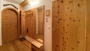 Une pièce en bois avec un grand miroir, un banc en bois et une porte dotée d’un miroir.