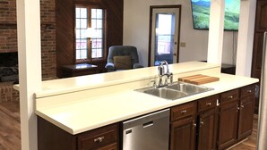 Una cocina moderna con lavavajillas de acero inoxidable, armarios de madera y un ventanal grande.