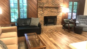 Una sala de estar acogedora con chimenea de ladrillo, sofás de cuero y piso de madera.
