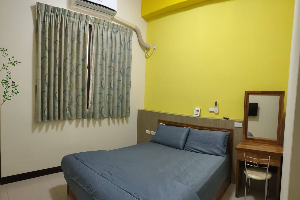 Una camera da letto con un letto, una scrivania, una sedia, un condizionatore d'aria e uno specchio.