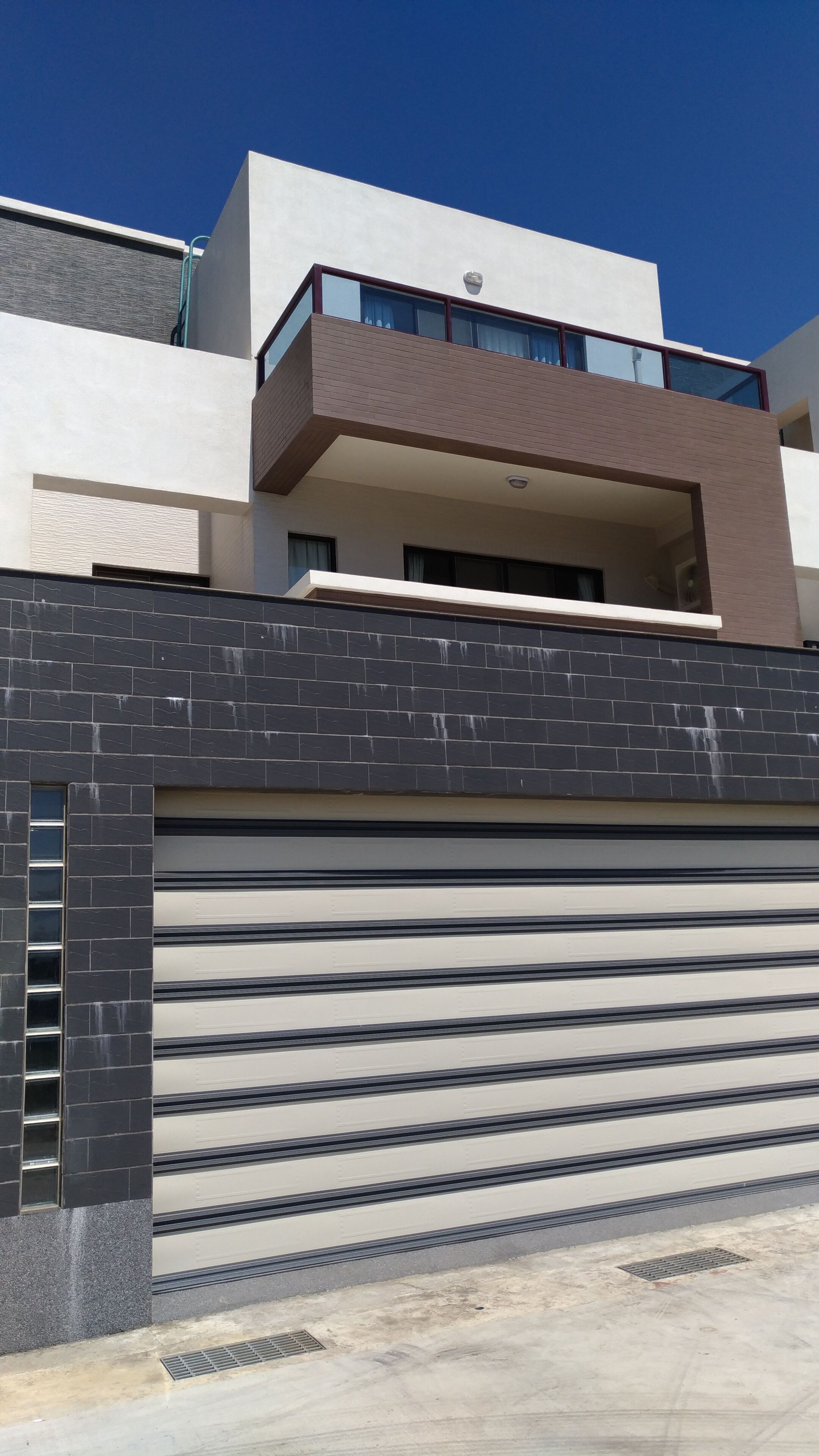 A modern building with a flat roof, large windows, and a garage door.