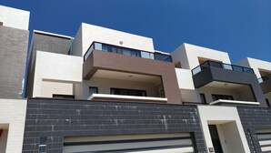 Un moderno edificio residencial de varios pisos con garaje, balcones y una combinación de ladrillo y paredes lisas.