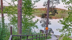 A wooden dock extending into a calm lake, surrounded by trees and a no-swimming sign.