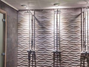 Un baño con pared texturizada y tres duchas superiores.