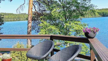 Une terrasse en bois avec deux fauteuils en osier et une plante en pot.