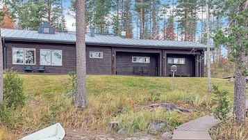 A cabin with a metal roof, two visible windows, and a dock with a boat.