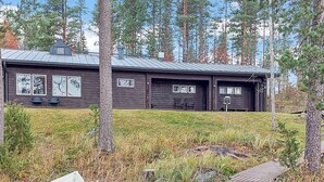 A cabin with a metal roof, two visible windows, and a dock with a boat.