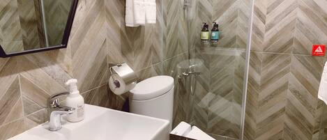 Une salle de bain avec un lavabo, des toilettes et une douche, le tout de couleur blanche.