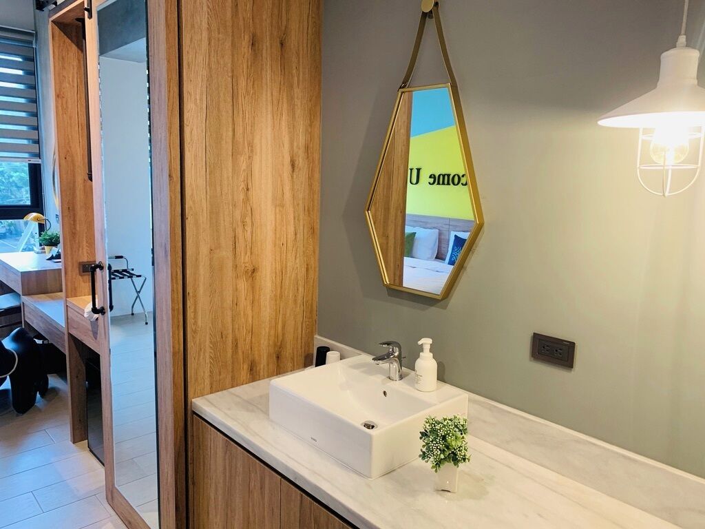 A modern bathroom with a wooden vanity, a white sink, and a mirror with a geometric frame.