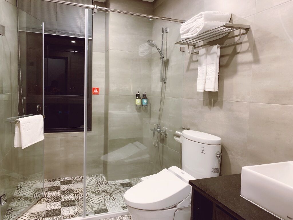 A modern bathroom with a glass-enclosed shower, a white toilet, and a tiled floor.