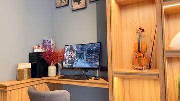 Un espacio de oficina moderno con un escritorio de madera, un monitor de computadora, un teclado, un violín y decoración en la pared.