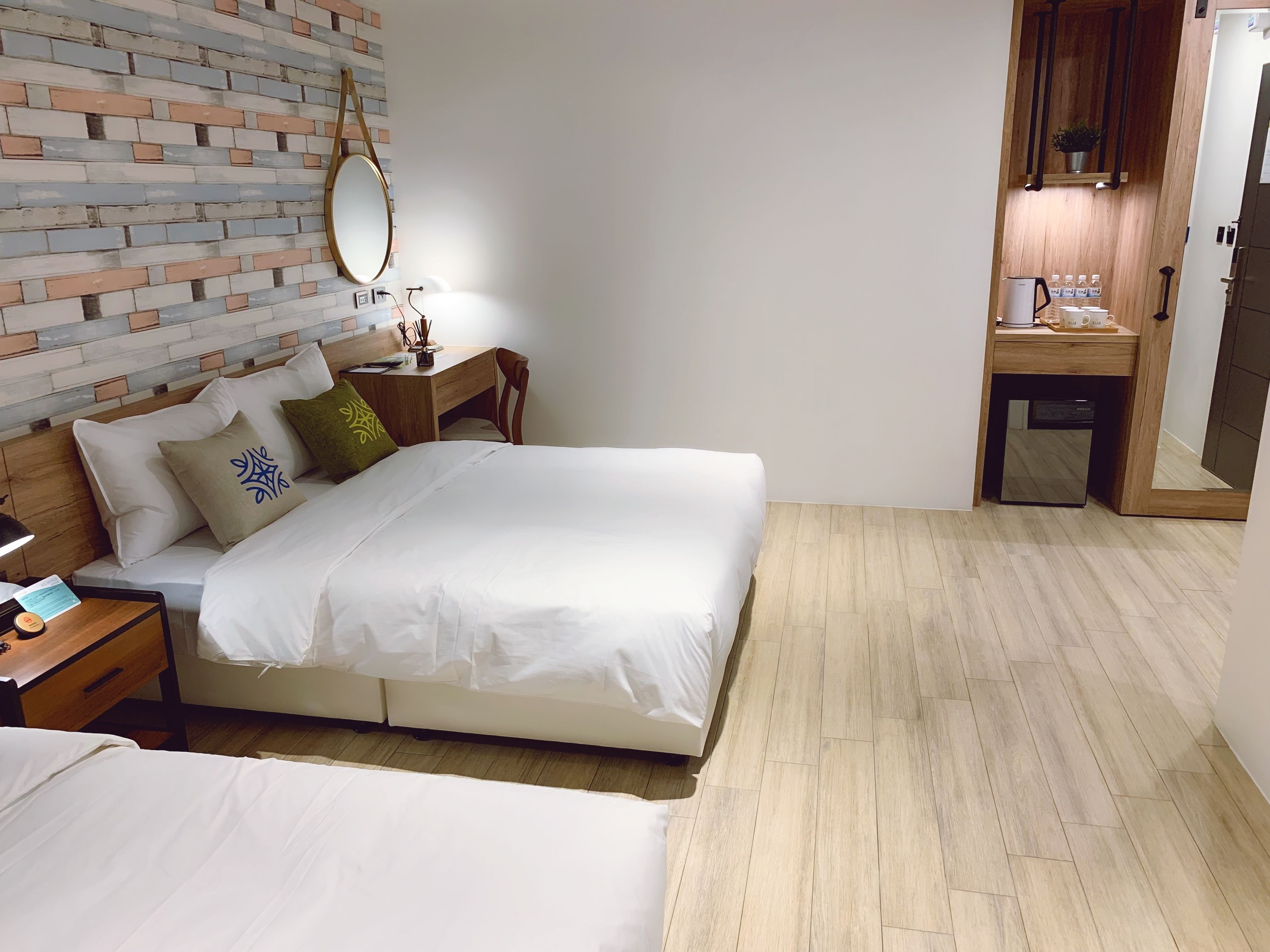 A hotel room with a bed, bedside table, and a small desk with a mirror.